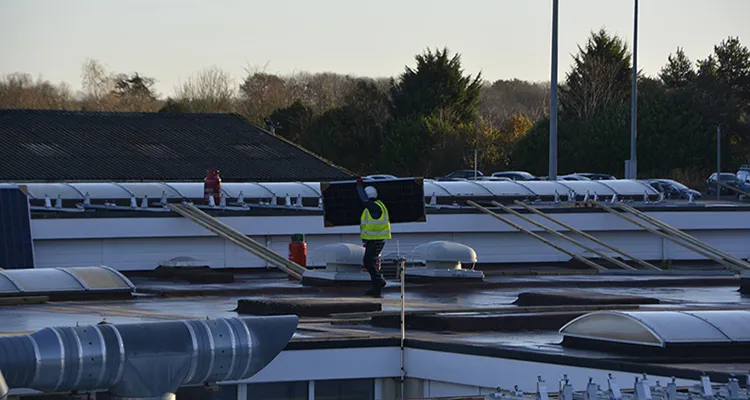 Worker carrying solar panel to be installed on the roof of the Engineering & Construction Centre